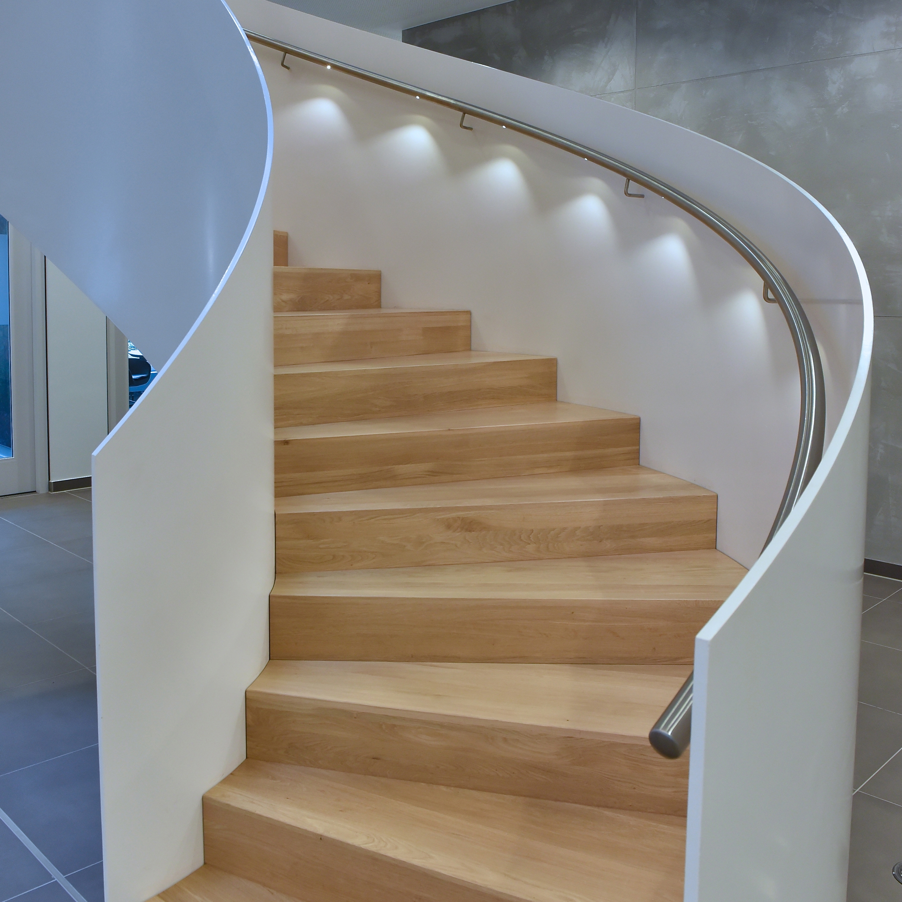 Mostra il prodotto Impressively rounded stringer stairs with LED lighting at Norderstedt Bank del produttore MetallArt Treppen