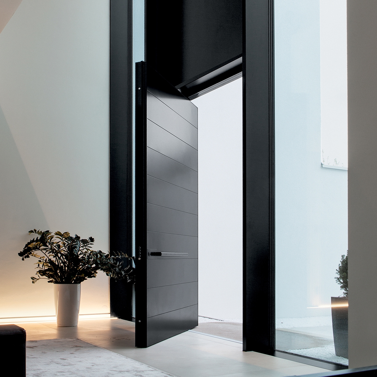 Display product Synua | The safety door for large dimensions, with vertical pivot operation and installation coplanar with the wall. from manufacturer Oikos Venezia – Architetture d’ingresso