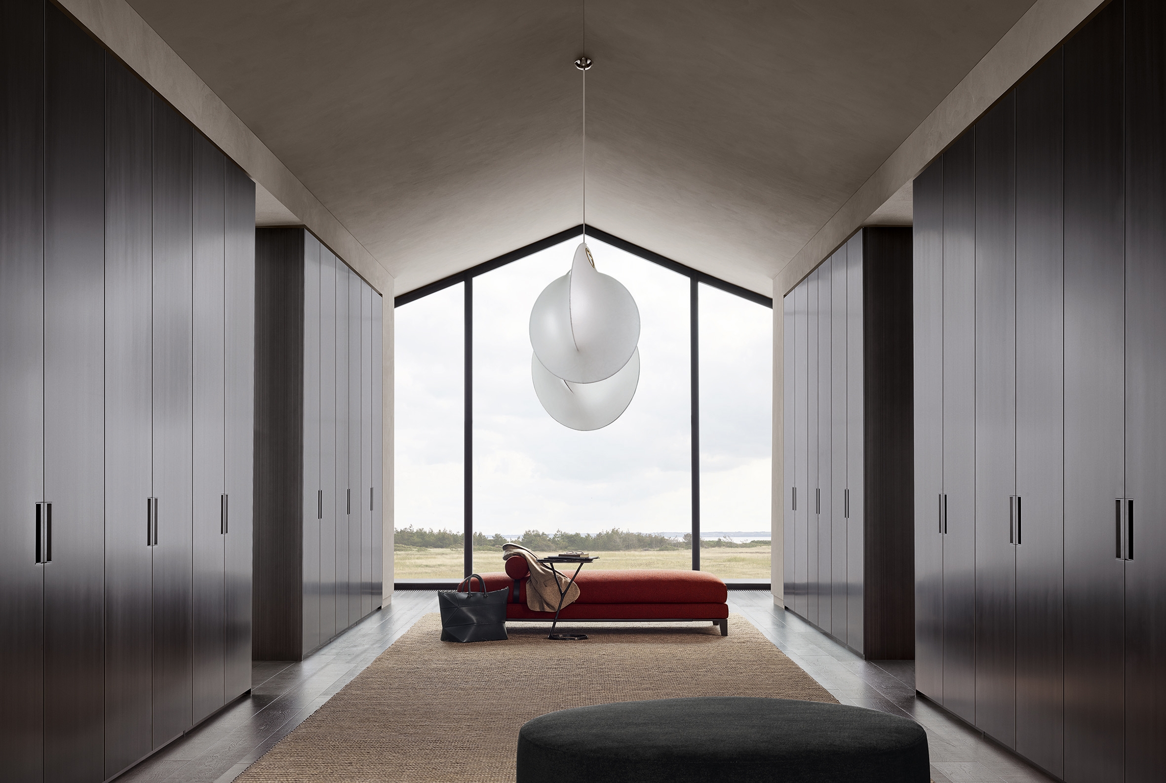 The sleek surfaces of the Senzafine Plus wardrobe by R&D Poliform contrast with Massaud’s soft New York pouffe and sumptuous, rust-coloured Bellport daybed