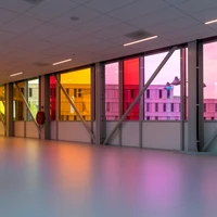 Daylight filtering through the translucent walls casts colourful patterns on the floor, creating an uplifting experience as visitors move between the buildings