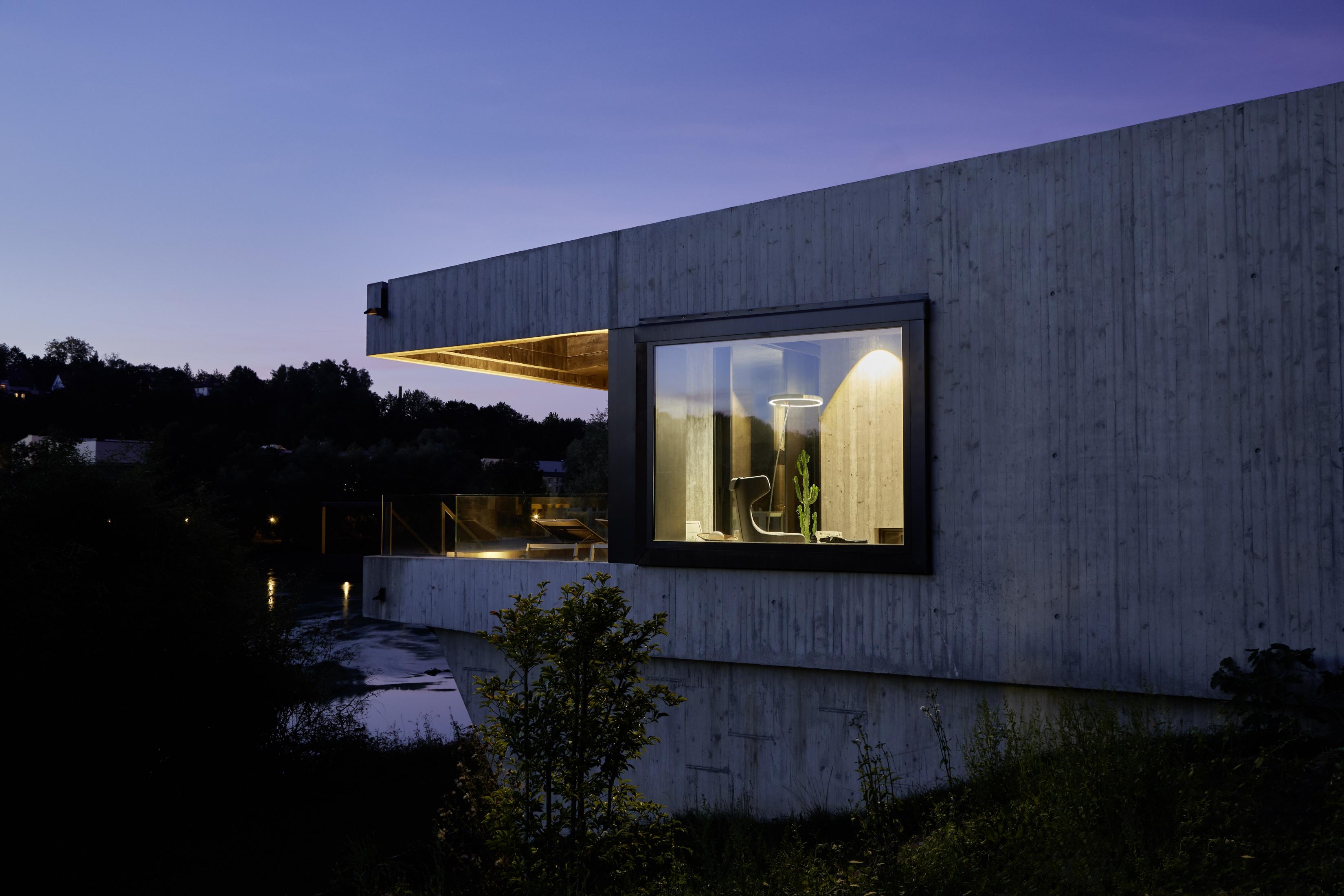 The house, in a spectacular location above the Inn River, is made entirely of rough, exposed, concrete formwork and has a black interior. The Occhio luminaires create a lively interplay of light and texture on the raw concrete walls