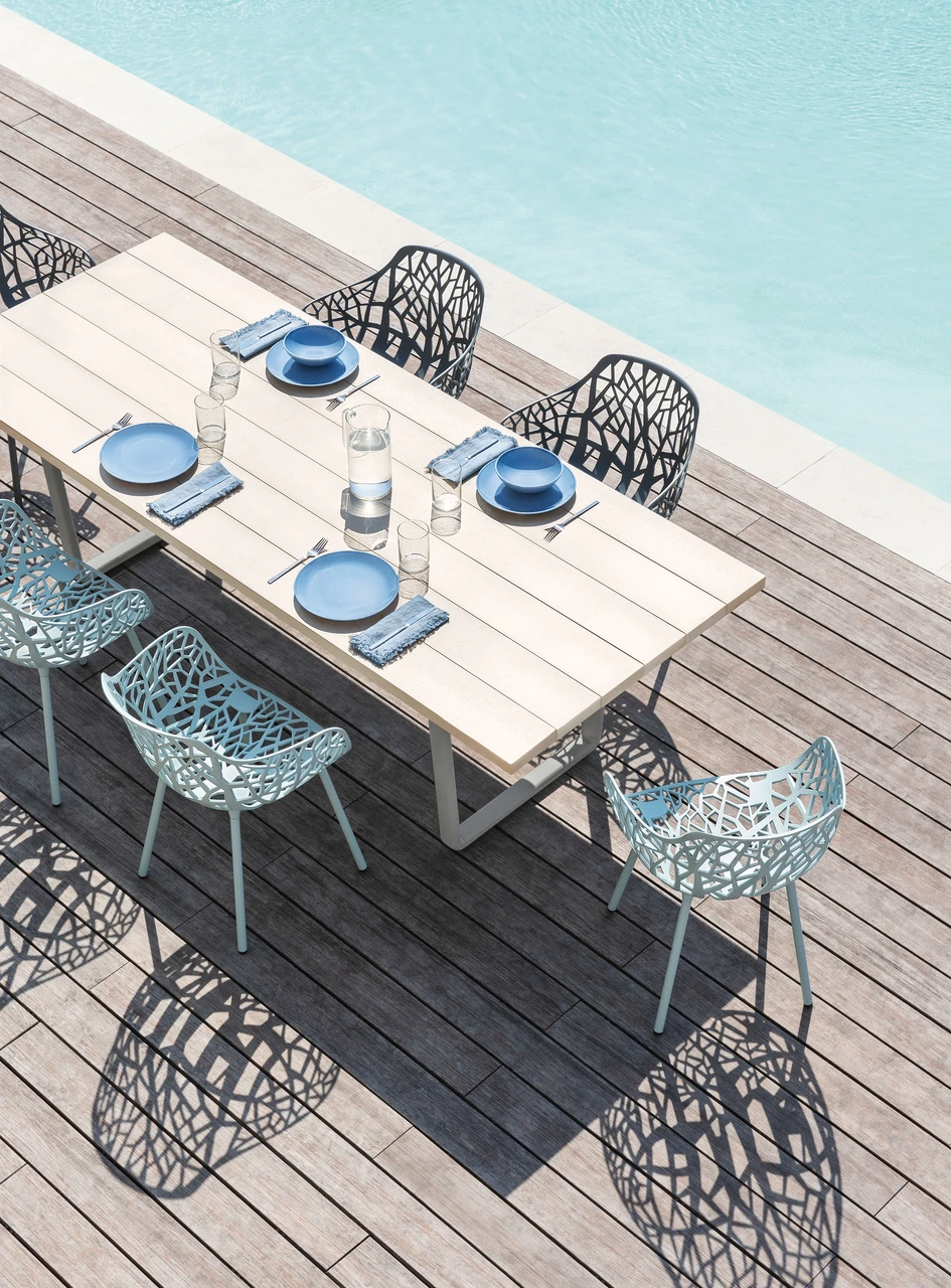 Der widerstandsfähige Aluminiumtisch Orizon, hier am Pool zwischen einigen Forest-Stühlen, wurde mit dem einzigartigen NaturAll Holzeffekt-Finish von Fast versehen und macht eine respektvolle Verbeugung vor traditionelleren Gartenmöbeln aus Holz
