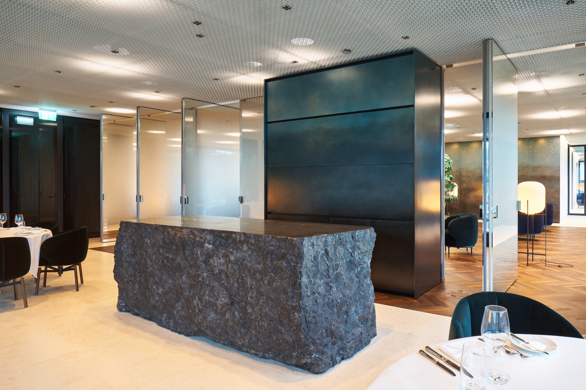 A partially mirrored, smoked-glass wall – made up of pivoting panels – allows the creation of a more expansive interior volume, if required, and increased circulation and longer sightlines