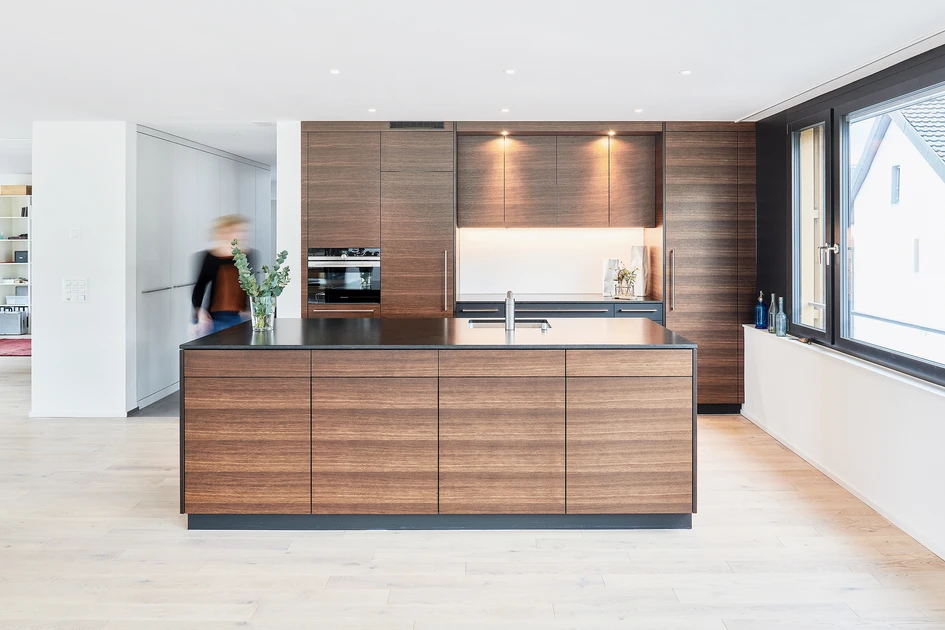Edel eleganter Materialmix: Die satinierte Granitabdeckung harmoniert perfekt mit den Fronten aus Räuchereiche