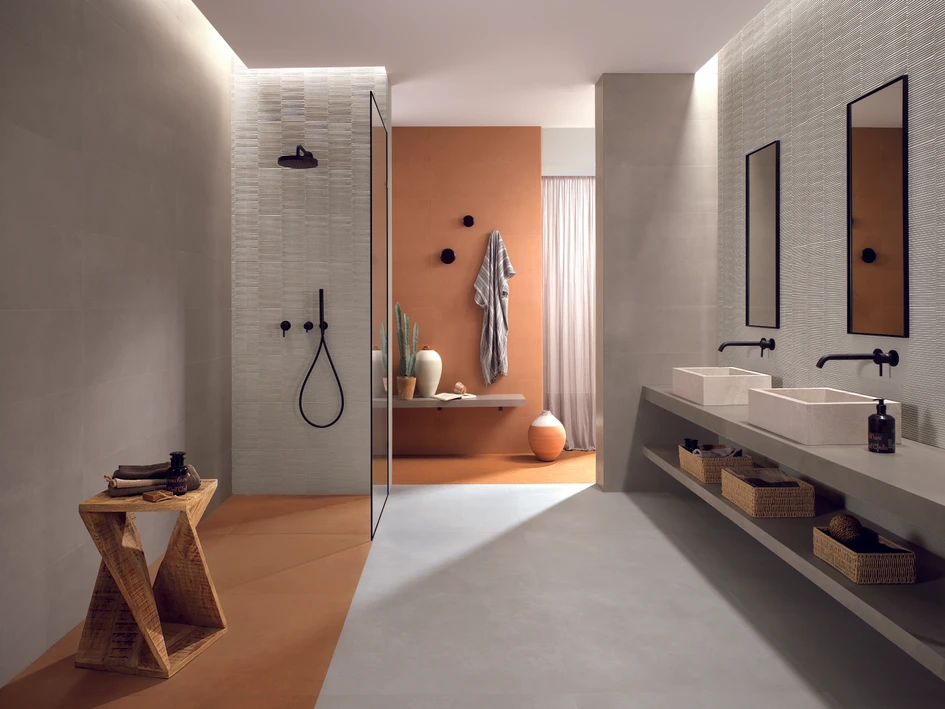 Warmes Terracotta und elegante graue Ombra- und Vento-Fliesen bringen Form in dieses Bad. Das 3D-Motiv Slot Vento bedeckt die Wände der Dusche und des Waschbeckens für zusätzliche Textur
