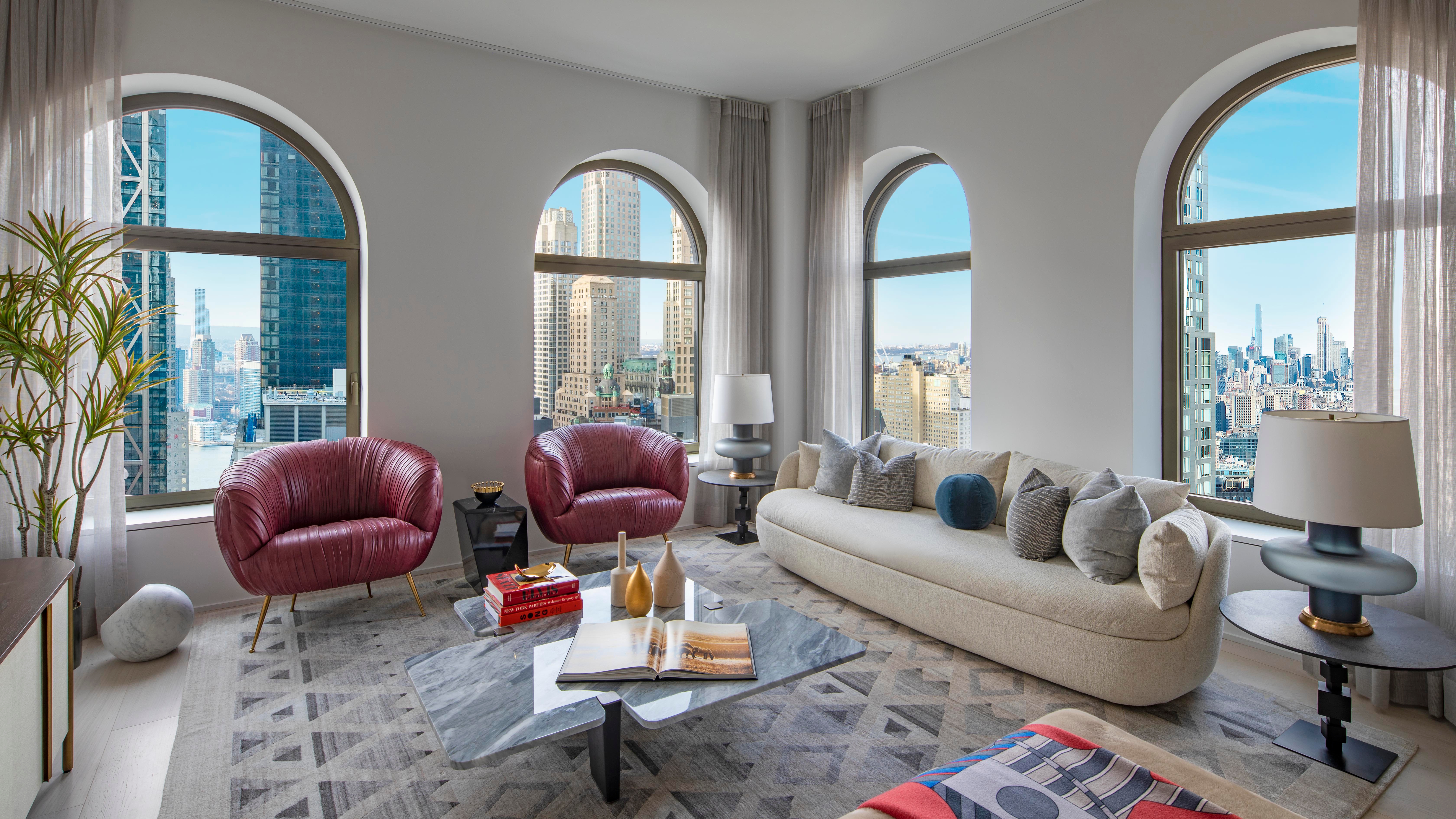 Model residences complement the architecture with expertly curated furnishings, such as the Pierre Frey custom-curved, brass-based sofa (top), and Kelly Wearstler’s Souffle chair in oxblood red (below)