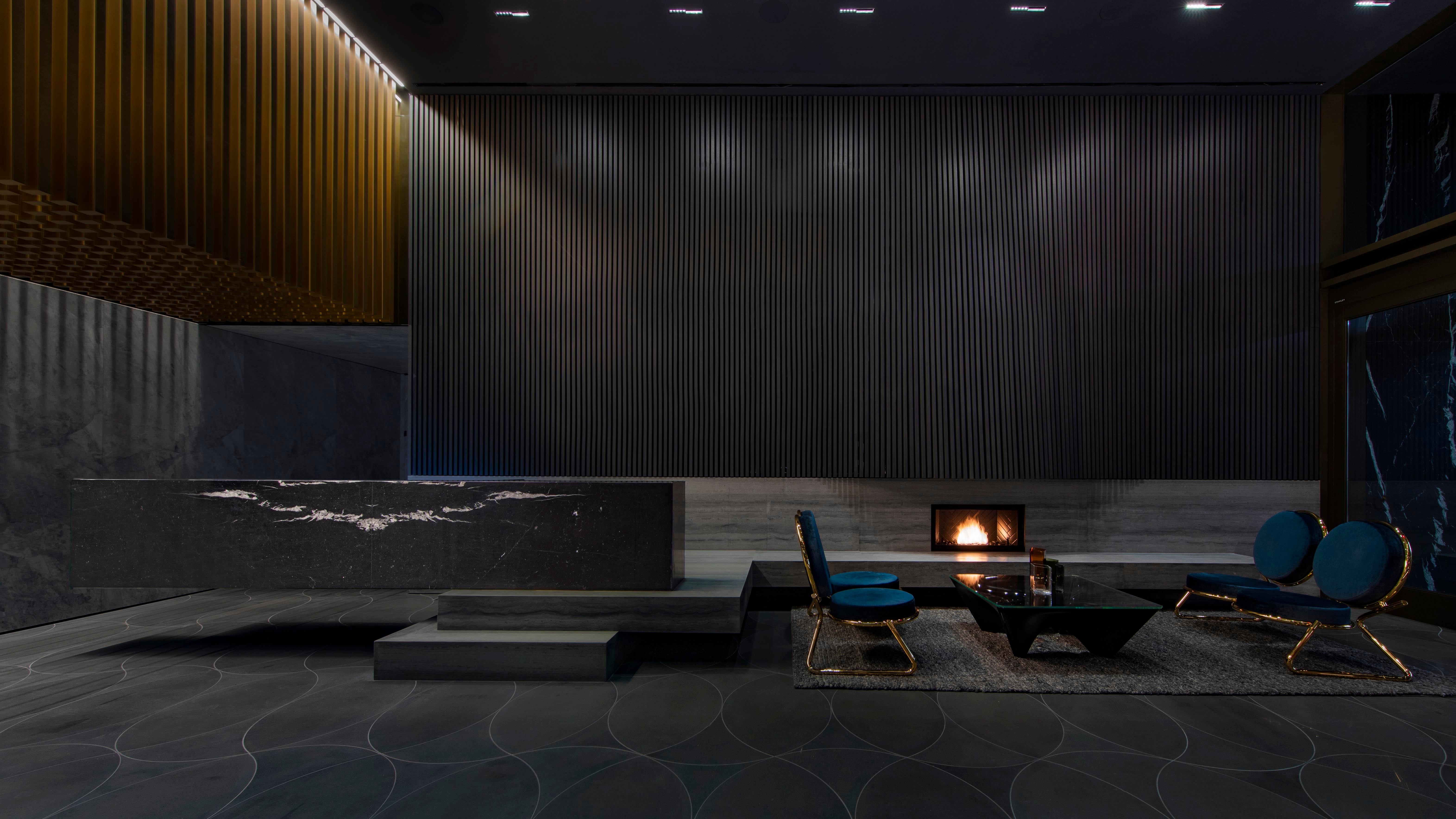 The language of the exterior architecture extends into the lobby. A feature wall picks up the arch motif with up-lit nooks showcasing books and decorative objects, and fine bronze detailing continues throughout
