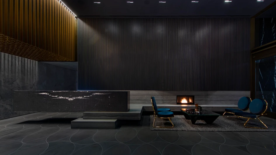 The language of the exterior architecture extends into the lobby. A feature wall picks up the arch motif with up-lit nooks showcasing books and decorative objects, and fine bronze detailing continues throughout