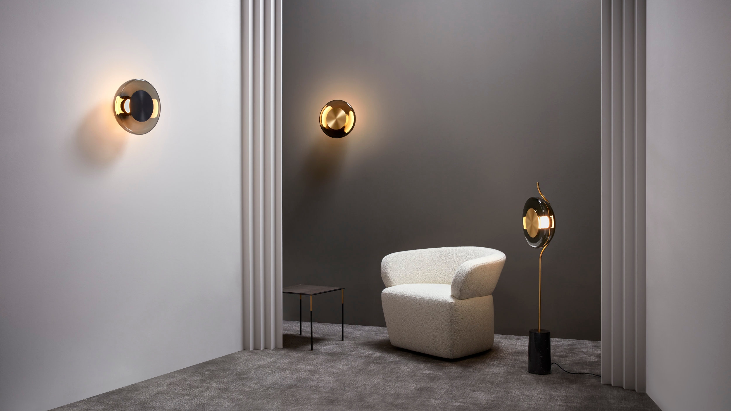 From an LED core, concealed behind a disc of satin brass or bronze finish, an oscillating, other-worldly light diffuses through the rounded, tinted glass of the shades