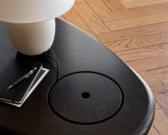 The tactile top is made from dark oiled oak, polished to a shine, with the grain following through the lid of the storage compartment. The cylindrical leg is made from steel