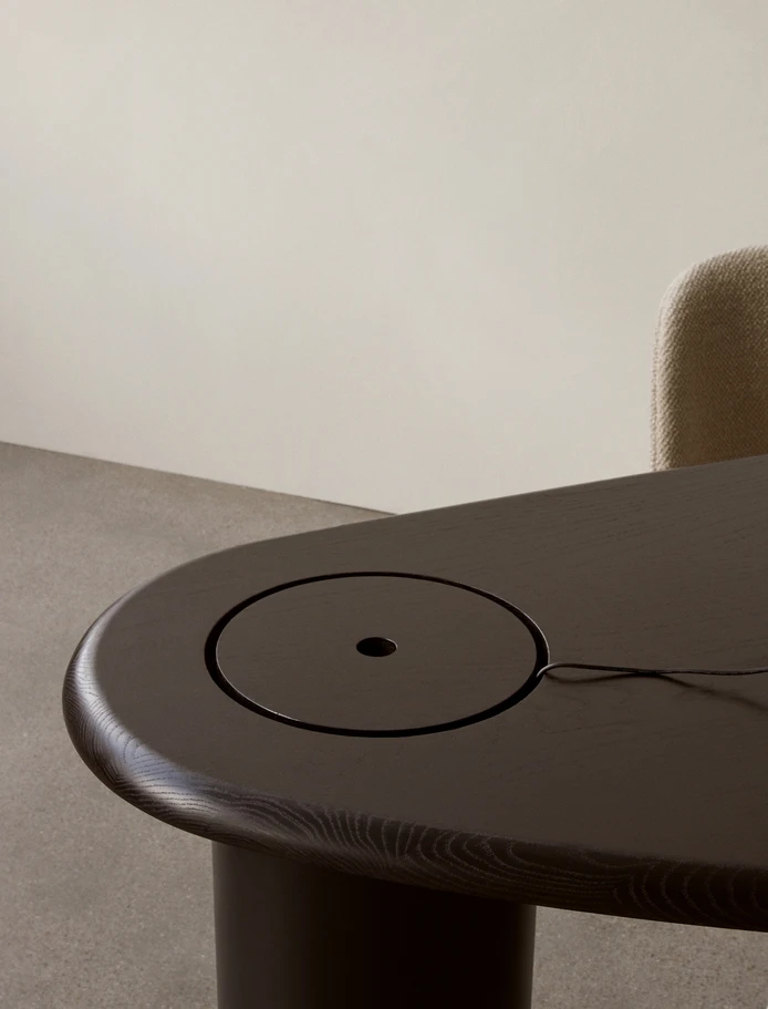 The cylindrical leg provides practical storage space for wires and office ephemera, which is closed off with a circular lid, embedded discretely into the surface of the desk
