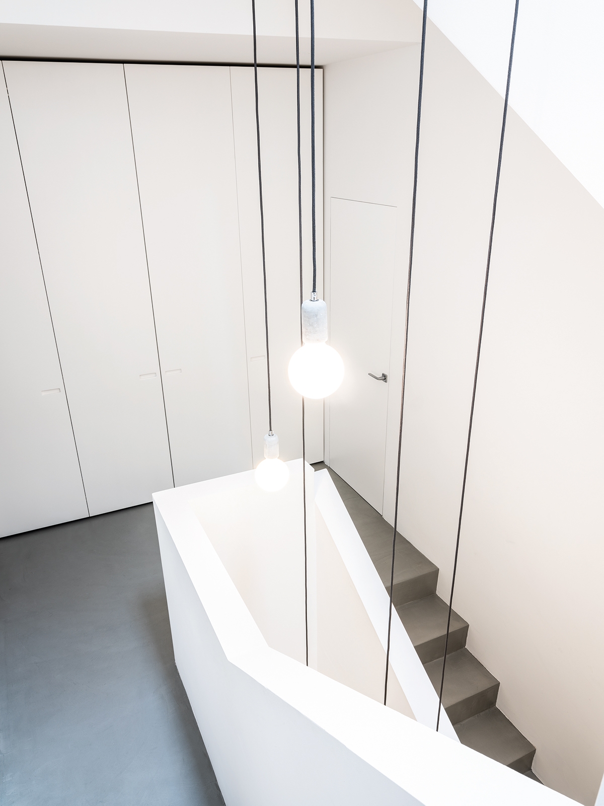 The doors are lacquered to blend with the surrounding walls. It creates a blank canvas against which features such as sculptural lighting installations can shine