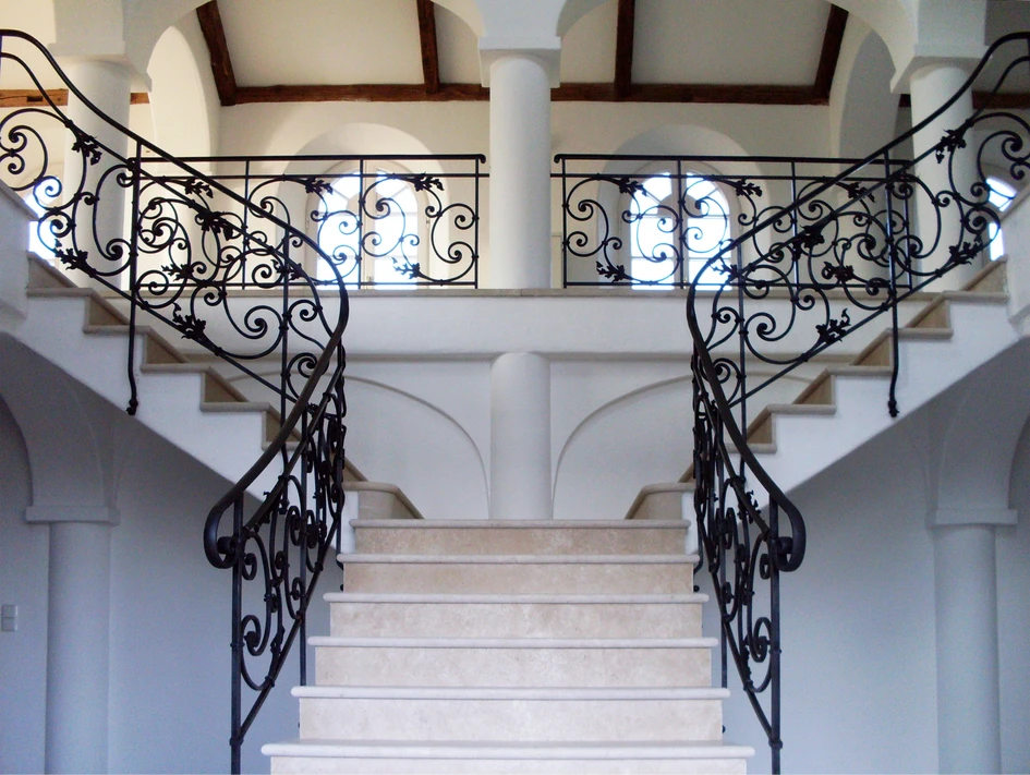 Bifurcated staircases split out as they rise, offering two access points to the upper floor