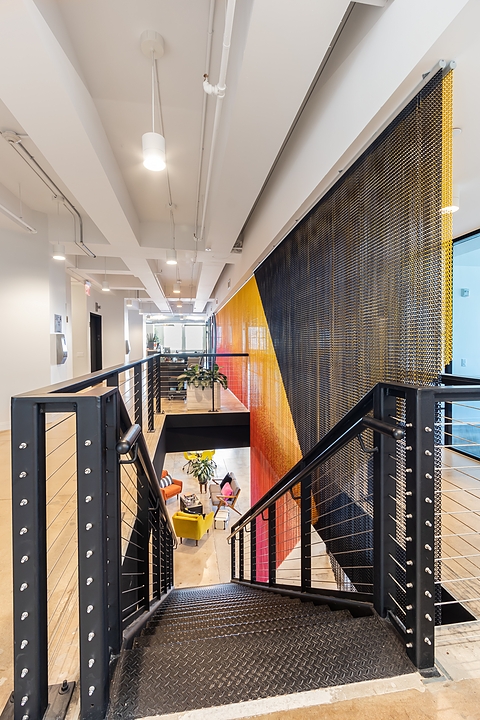The vibrant colour of Kriskadecor's aluminium chain partition is a colourful accent in the MiQ office interior
