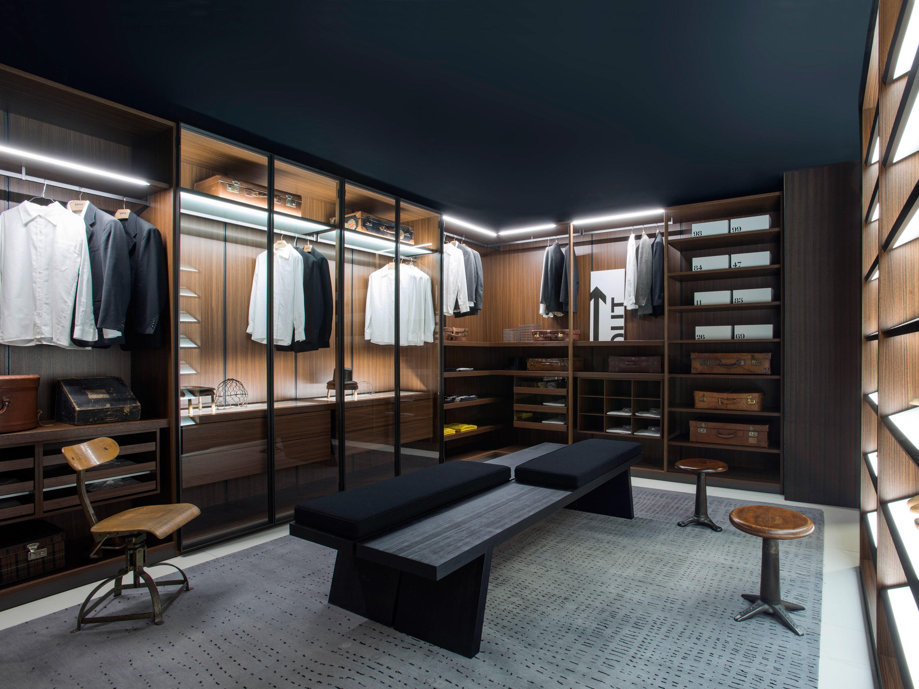 Walk-in wardrobe storage solutions, like this example from Porro, combine storage for clothes, accessories and additional objects with seating and a cosy atmosphere