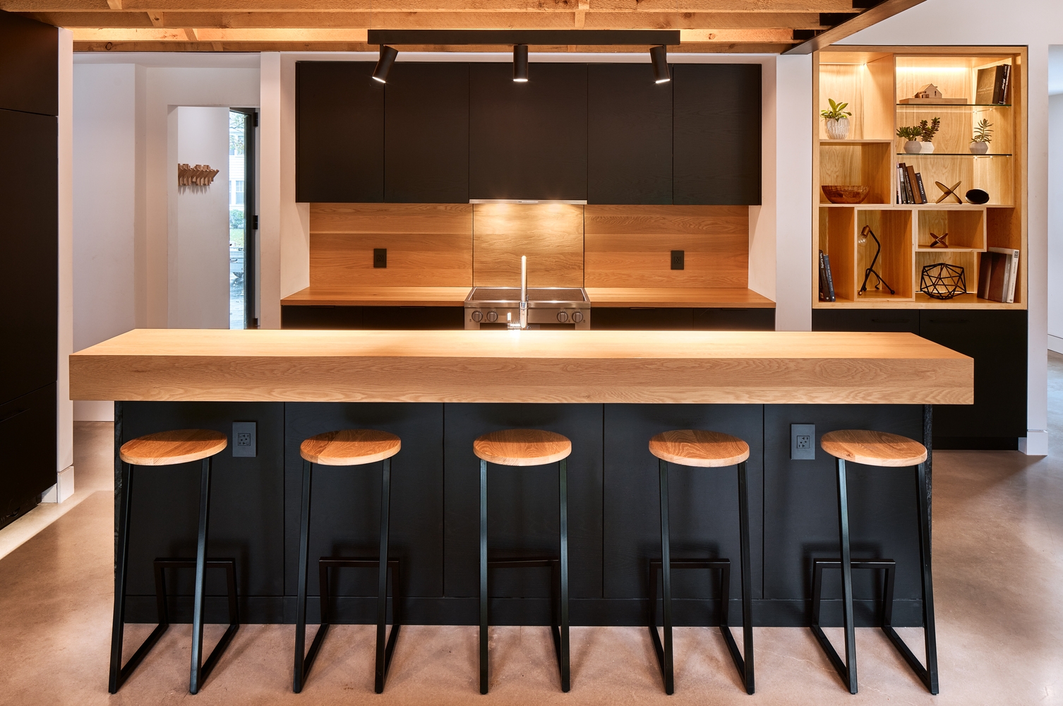The dark Armcrescent Residence kitchen combines black cabinetry with warm, custom-fabricated wooden elements. Photo: Julian Parkinson