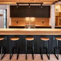 The dark Armcrescent Residence kitchen combines black cabinetry with warm, custom-fabricated wooden elements. Photo: Julian Parkinson