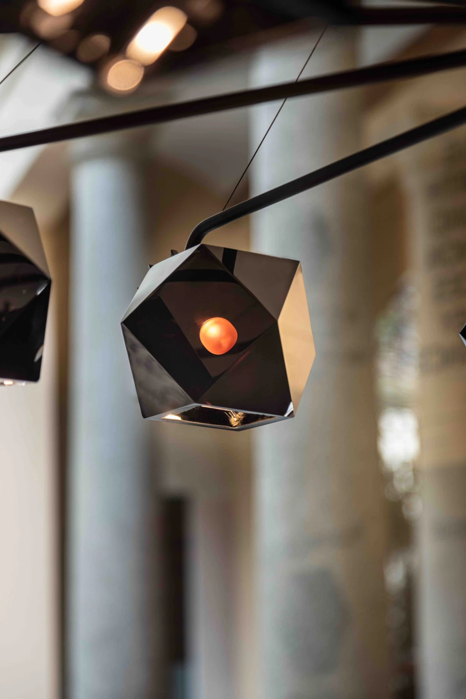 David Rockwell’s version of the Welles (top) groups the light fixtures in an organic cluster like grapes, while Alessandro Munge’s take (below) shows them dancing at the end of long black limbs