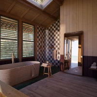 Alongside the wooden backdrop, soothingly toned travertine bathtub and washbasins, and tiles of emerald green and aubergine combine with the warm glow of the fittings' PVD surfaces