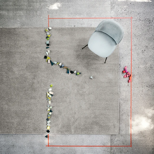 The Rugx Smoozy variant in a warm grey tone, staged with colourful building blocks. Over 70% of the Rugx products are already made from recycled Econyl yarn and have been awarded the Blue Angel label 