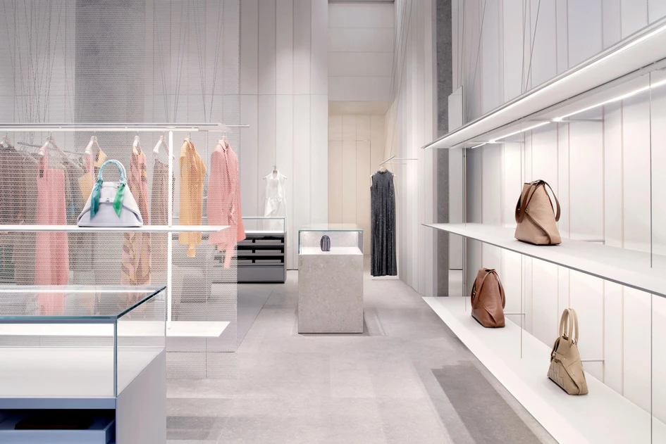 Pre-shaped wood panelling and grey limestone flooring provide the backdrop for the AKRIS concept store’s system of suspended shelves and hangers. Photos: Alberto Parise
