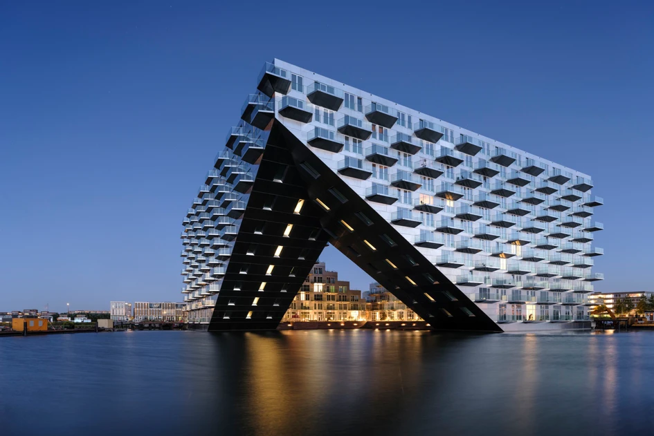 Built on the IJburg harbour in Amsterdam, the Sluishuis connects the water and the city, projecting its sloped facade into the sea at a cantilevered front corner. Photo: Ossip van Duivenbode