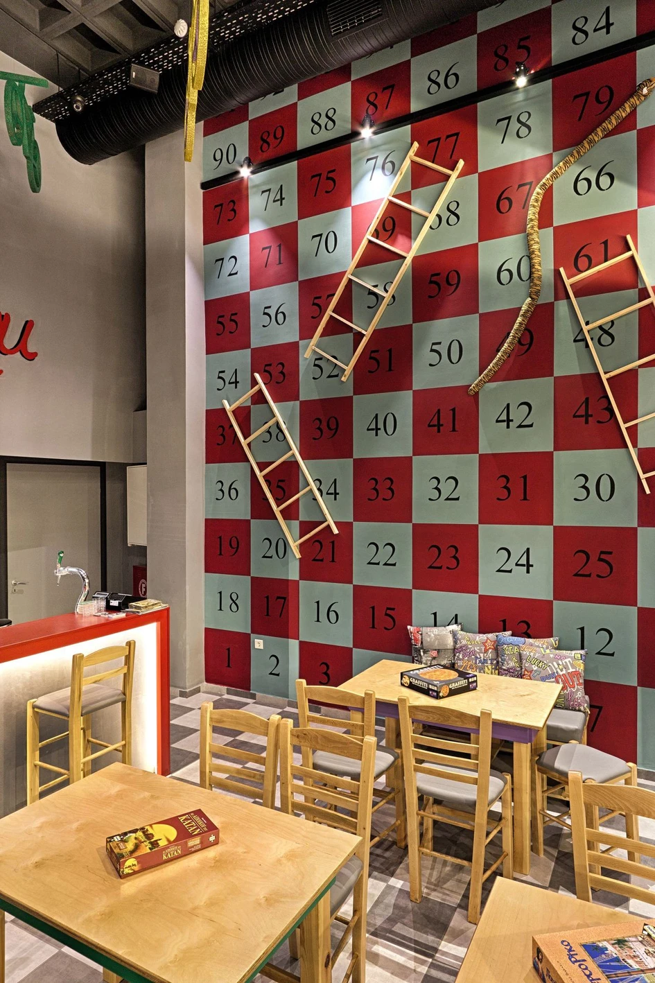 The Alaloum Board Café combines functional furniture choices such as wide tables and comfortable-backed seating with childhood-referencing decorative surfaces. Photos: Dimitris Kleanthis