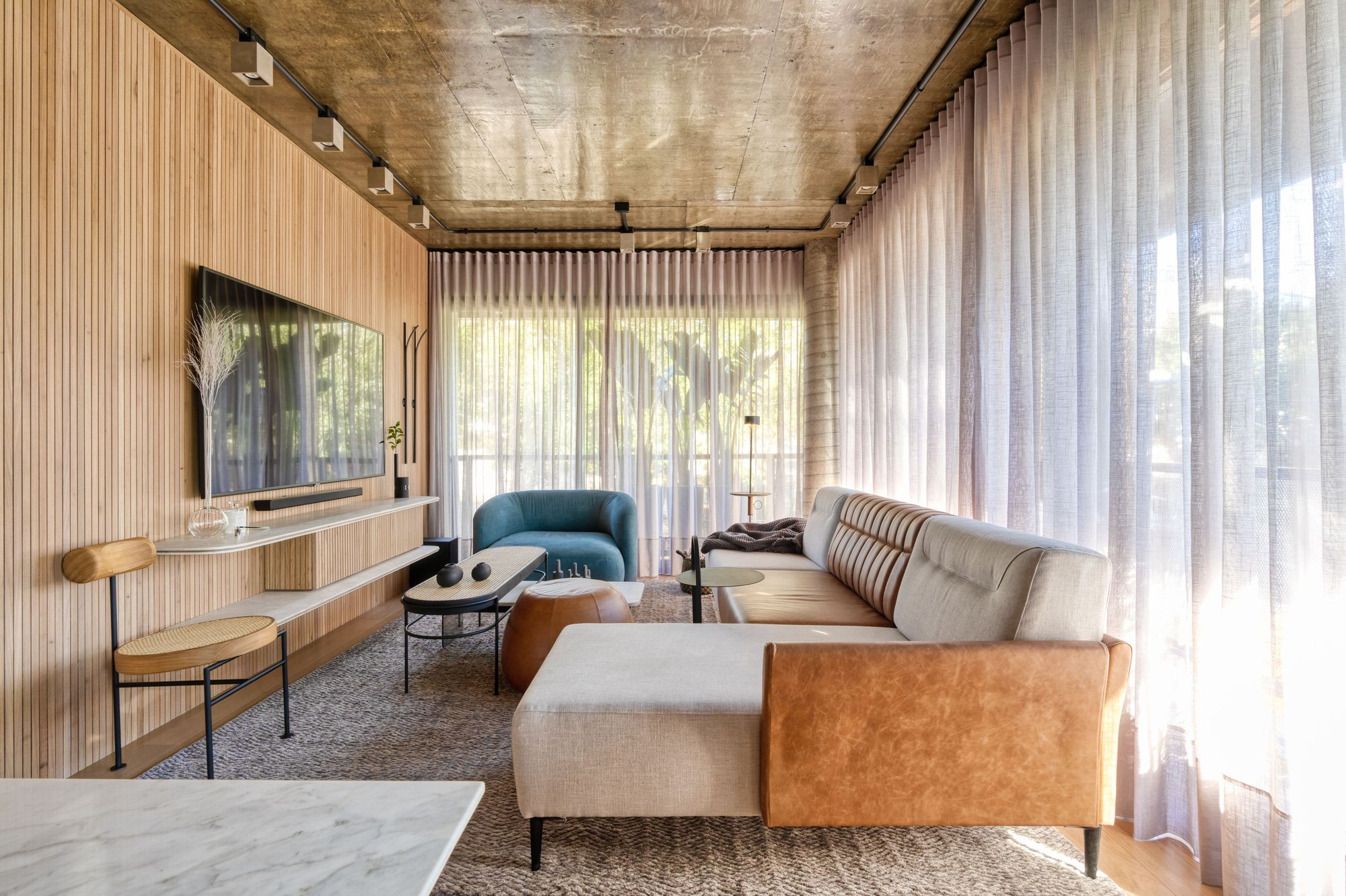 Light translucent full-length curtains draw texture and depth across the edges of the Loft Chartier’s living space by Studio Colnaghi Arquitetura. Photo: Vinicius Ferzeli