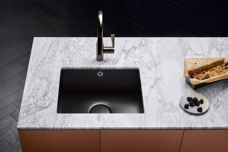Under-mount sinks like this black glazed-steel sink from Dornbracht extend the worktop and simplify cleaning up, while matching or contrasting with the rest of the space