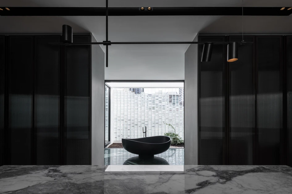 Next to a glass-block wall, Interlude House’s black tub is naturally well lit in the day, but the dark surfaces surrounding it change the atmosphere at night. Photo: Chalermwat Wongchompoo