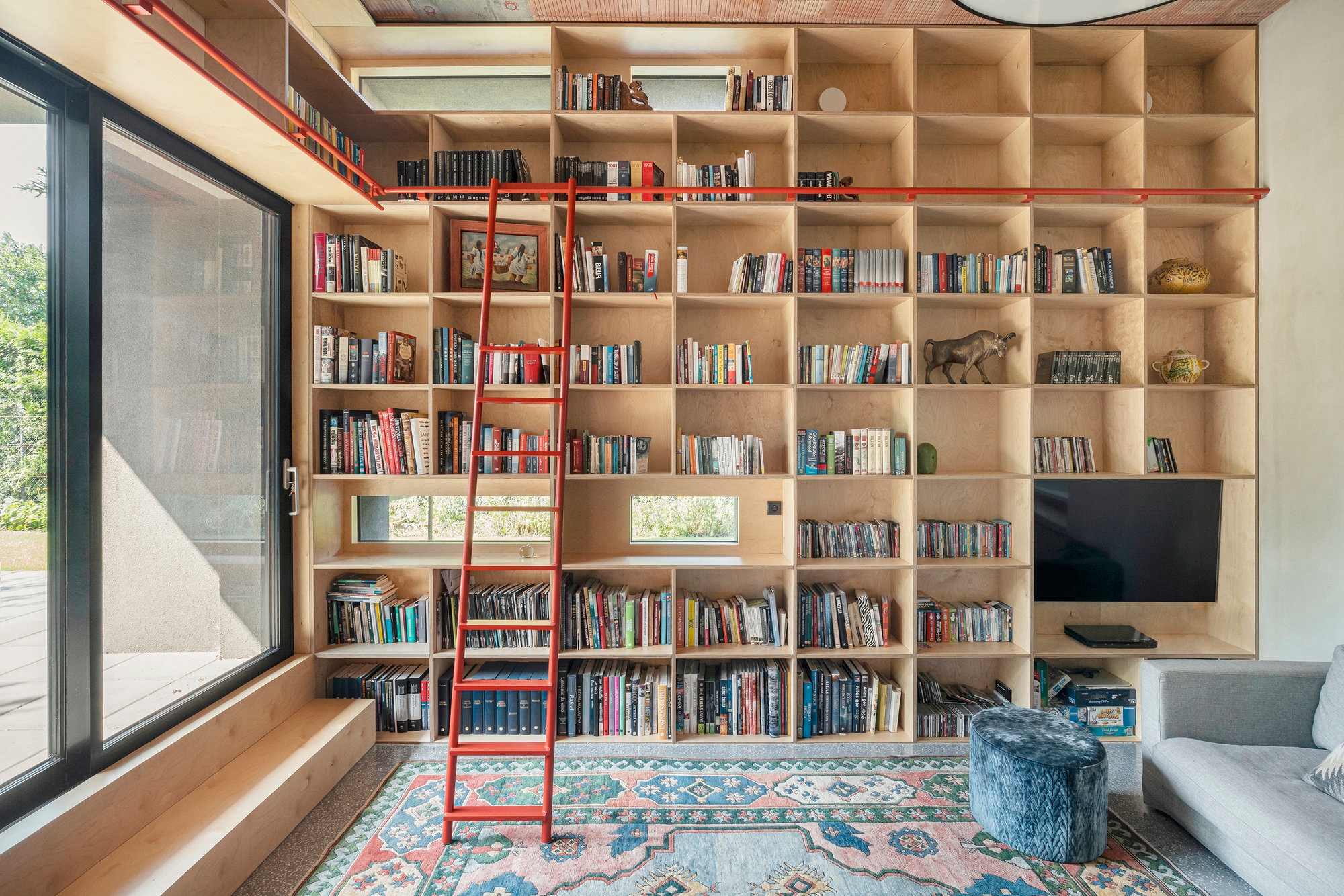 A scene-stealing red track ladder allows the reading room of Zosia’s House dress head to toe in books, without feeling overbearing. Photo: Kroniki.studio