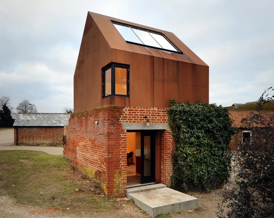 The rusted hue of the Cor-Ten steel in Haworth Tompkins Architects's Dovecote Studio project is similar to that of the red brick farm buildings nearby; photo: Philip Vile