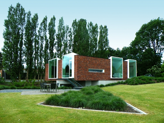 The sides of the building facing onto the street are largely closed off, while expansive windows frame views of the surrounding landscape on the other sides; photo: Atelier Vens Vanbelle