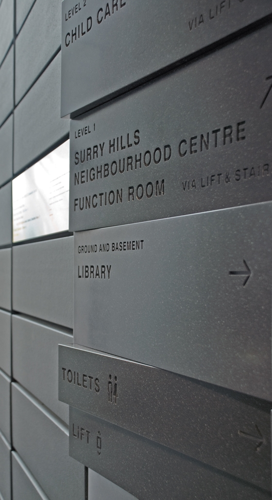 Die Signaletik in Sydneys Surry Hills Library & Community Center stammt vom Studio Collider. Sie prägt die Architektur des von FJMT entworfenen Gebäudes mit. Mit der gewinkelten Anordnung der Blöcke wird angedeutet, in welcher Richtung die Ziele liegen