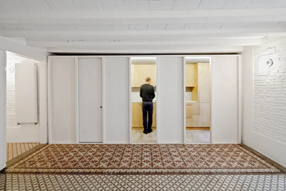 Renovated apartment in Barcelona, featuring polished mosaic floors that reveal the previous spaces within the original layout of the building