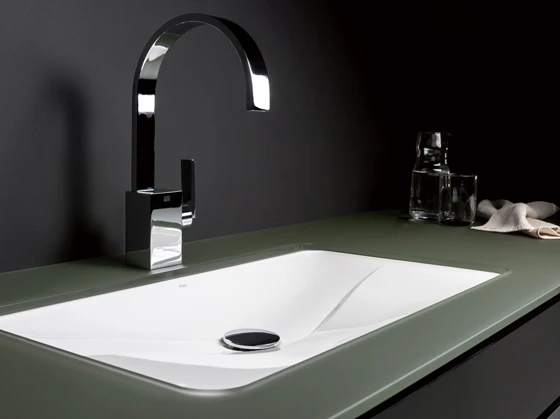 Unterbaubecken „EB.TA7000U - Tangens“ in Kombination mit einer Glasfläche. Das 694 mm breite und 381 mm tiefe Becken mit der eleganten Welle ist nur 77 mm hoch