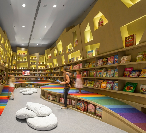 Im Untergeschoss ist die Kinderbuchabteilung untergebracht. Eine mit vielfarbigen Streifen bemalte Rampe zitiert augenzwinkernd den Bücherregenbogen aus dem Obergeschoss