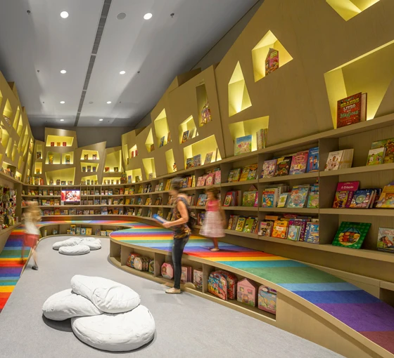 Im Untergeschoss ist die Kinderbuchabteilung untergebracht. Eine mit vielfarbigen Streifen bemalte Rampe zitiert augenzwinkernd den Bücherregenbogen aus dem Obergeschoss