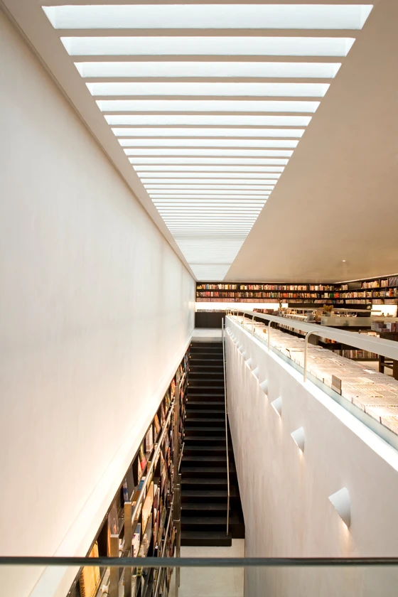 Innenansicht der in einem recht schmalen, ursprünglich zweigeschossigen Gebäude untergebrachten Buchhandlung. Die oberen Ebenen haben keine Fenster, sondern Oberlichter, durch die Tageslicht einfällt