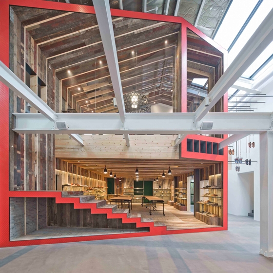 Inserted into an old warehouse, the new Camper shop is designed as a house within a house, viewed in cross section. The sliced-off ends have the same shade of red as Camper’s logo