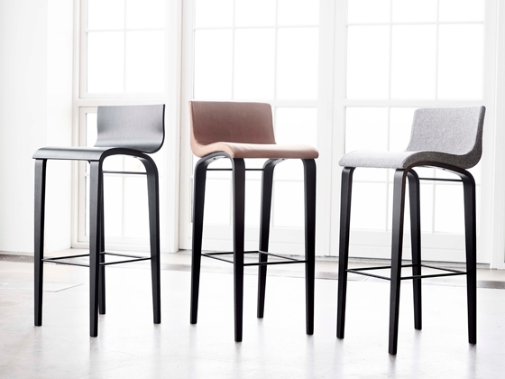 A black Copenhagen and two Curves barstools with upholstery in light grey fabric and cognac leather, stand tall on slender legs
