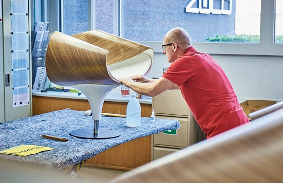 Der extravagante Loungesessel «Perillo» ist auf dem besten Weg, ein Designklassiker zu werden (oben). Die Formholzschale wird von einem Spezialisten geliefert und in der Werkstatt sorgfältig ausgepolstert (unten)