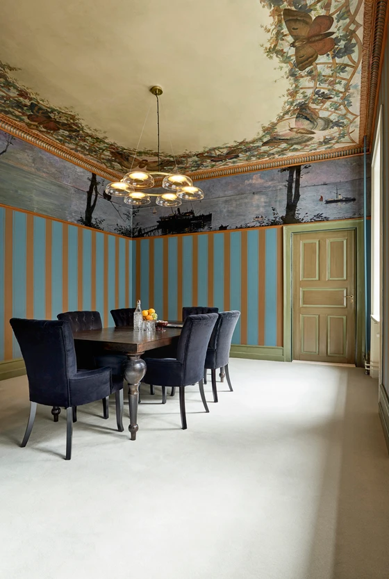 The neutral colour of the carpet is precisely the same as the base colour of the ceiling creating a silent backdrop to the impressive wall paintings.