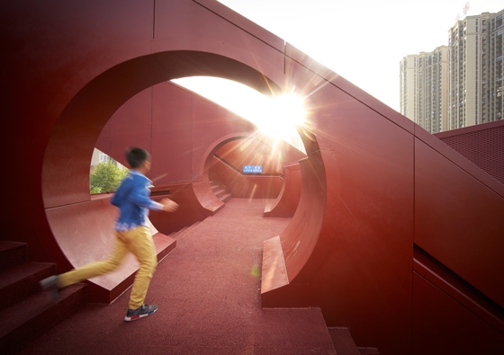 Circular openings punched into the side walls of the Lucky Knot bridge enable users to switch between the various routes. The curving structure touches the ground at several points to allow people to enter and exit wherever they like. Photos: Julien Lanoo